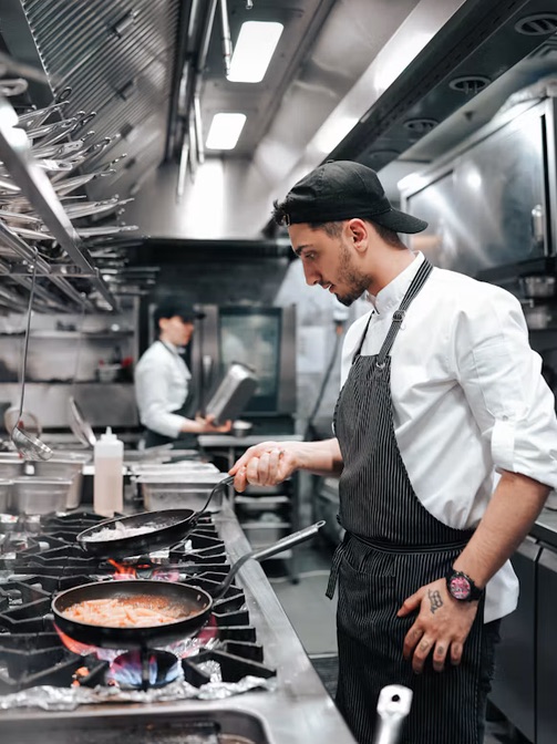 Chef cooking at a commercial gas range