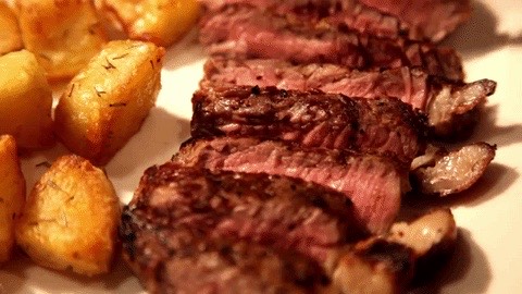 Sliced steak plated with roast potatoes