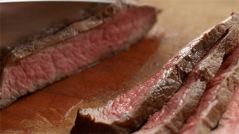 Slicing a cooked steak on a wooden board