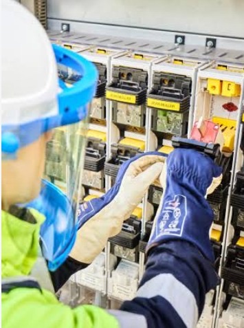 Technician in protective gear working on an electrical panel