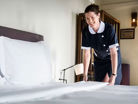 Housekeeper making a hotel bed