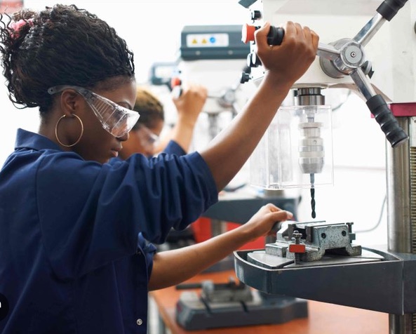 Trainee using a drill press in the workshop
